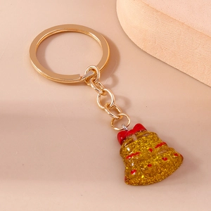 Detail of Christmas bell keychain with golden glitter and red bow on warm background
