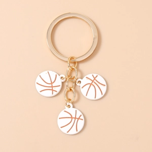 Détail de trois pendentifs de basket blancs avec attaches dorées sur un porte-clés sport