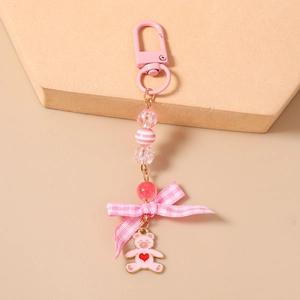 Close-up of beaded keychain with pink plaid bow and metal heart bear charm detail