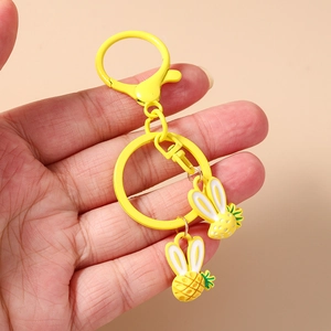 Detail von gelben Ananas-Hasen-Schlüsselanhängern mit Punkten und Blättern in der Hand