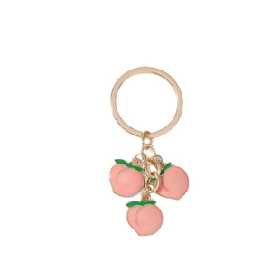 Fashionable golden keychain featuring three pink peach enamel pendants on a white background