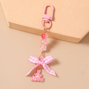 Detail view of a pink beaded keychain featuring a love pendant and checkered bow decoration