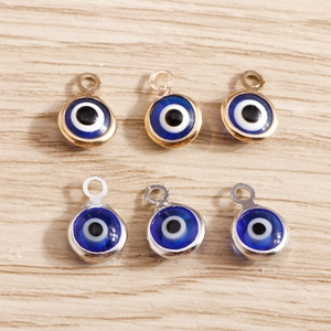DIY Evil Eye charms in gold and silver frames on light wood background for jewelry making