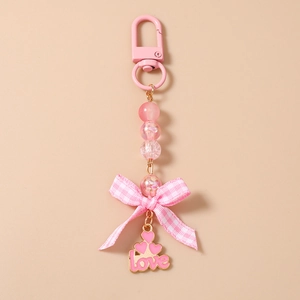 Detail of pink beaded keychain with a checked bow and golden edged heart love pendant
