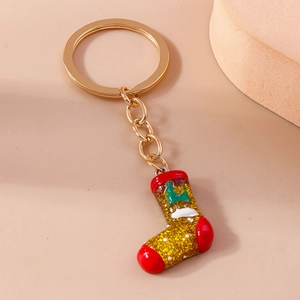 Macro view of Christmas stocking keychain with gold glitter, red trim and green tree icon