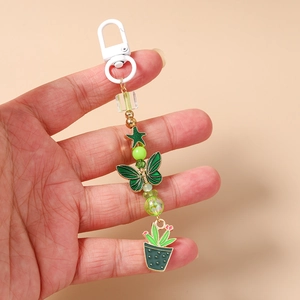 Détail d'un porte-clés à perles vertes avec pendentifs papillon et cactus stylisés