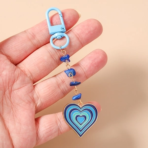 Détail de perles turquoise et pendentif coeur en émail sur un porte-clés doré chic