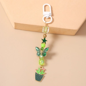 Détail d'un porte-clés perlé vert avec pendentifs en émail étoile de mer et papillon