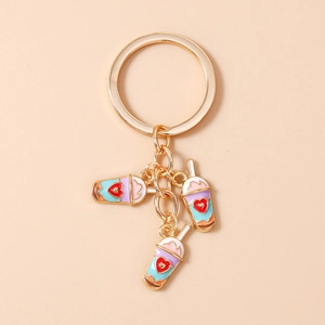 Close-up of golden keychain with three colorful milk tea charms and red heart details
