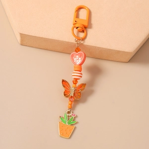 Détail du porte-clés perlé orange avec breloques papillon cactus et décor cœur