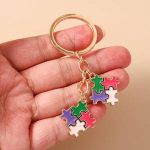 Détail de porte-clés puzzle cœur colorés en émail avec des maillons en métal doré