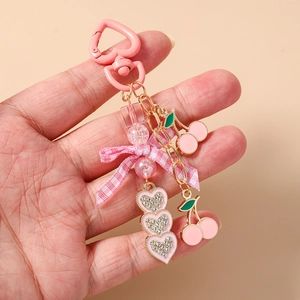 Handheld pink heart keychain with cherry charm and plaid ribbon bow accessory