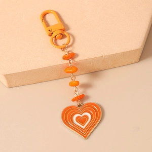 Détail d'un porte-clés cœur orange avec chaîne à perles et fermoir mousqueton robuste