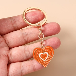 Détail d'un porte-clés en émail orange et blanc en forme de cœur avec chaîne dorée