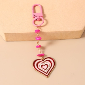 Détail d'un porte-clés en émail rose en forme de cœur avec chaîne perlée et fermoir doré