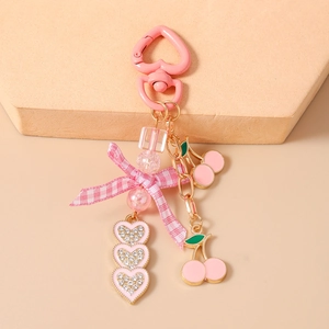 Close-up of pink cherry bow keychain with heart clasp and crystal studded charms