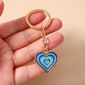 Gros plan d'un porte-clés en forme de cœur avec émail dégradé bleu dans la main