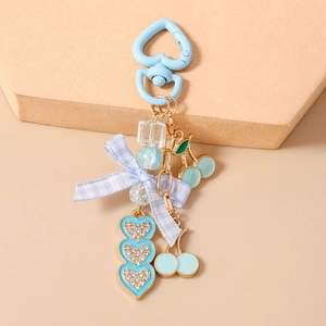 Detail of mint green cherry pendant and blue ribbon bow on the heart keychain