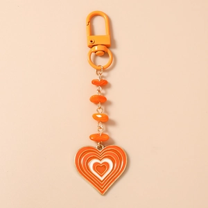 Détail du porte-clés cœur avec des perles en résine orange et pendentifs en forme de cœur