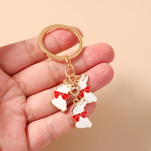 Détails de trois charms lapin en émail blanc avec nœuds rouges sur porte-clés doré