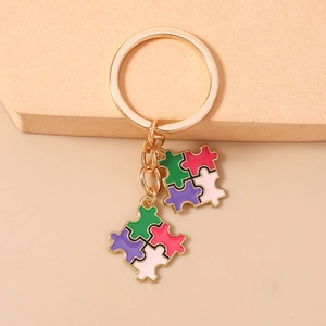Gros plan de charms puzzle colorés en émail sur un porte-clés doré sur pierre