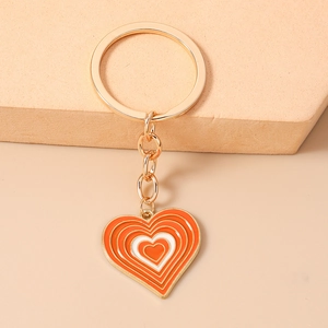 Détail d'un porte-clés cœur doré avec émail orange et blanc sur support pierre