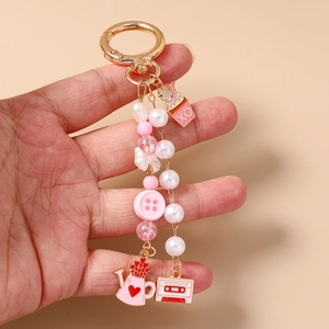 Close-up of pink beaded keychain with heart and star charms held in hand on orange background