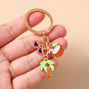 Detail of metal keychain featuring enamel palm tree, coconut drink, and heart sunglasses