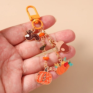 Detail of autumn squirrel and pumpkin charms on an orange metal keychain with beads