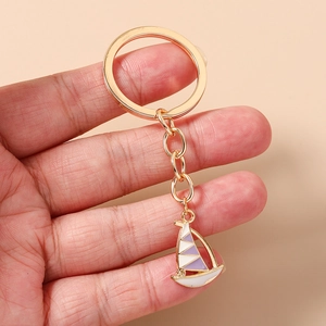 Detail of sailboat keychain featuring gold plating and purple enamel inlay on metal charm