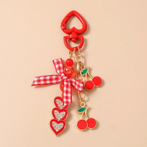 Detail of red heart carabiner with cherry charms, bow, and rhinestone heart pendants