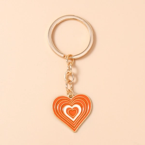 Détail du porte-clés en forme de cœur orange et blanc avec chaîne en métal doré