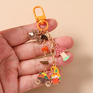 Detail of autumn-themed keychain featuring enamel squirrel, mushroom, and pumpkin charms