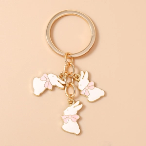 Détail d'un joli porte-clés en métal avec trois lapins blancs et des nœuds roses