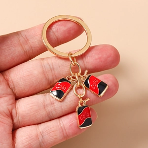 Close-up of mini Cola can charms with red enamel on a gold-tone metal keychain