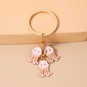 Dettaglio di un portachiavi dorato con tre ciondoli a forma di medusa rosa carina