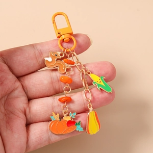 Detailed view of autumn-themed enamel keychain with squirrel, pumpkin and corn charms