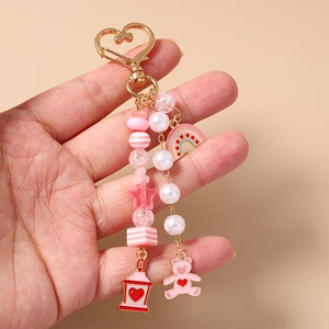 Close-up of pink beaded keychain with heart bear charm held in hand on warm background