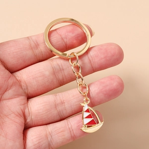 Close-up of golden sailboat keychain with red and white enamel on a circular ring