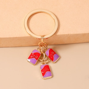 Detail of creative gold keychain with red and purple miniature soda cola can charms