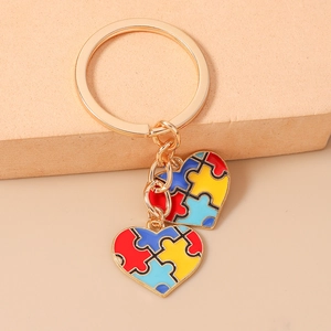 Détail d'un porte-clés puzzle cœur coloré avec anneau doré et finition en émail brillant