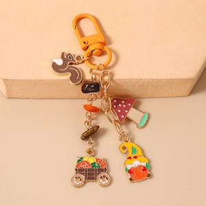 Detail of autumn enamel keychain featuring squirrels, gnomes, and pumpkin carriage charms
