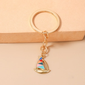 Detail of sailboat keychain featuring colorful enamel sails on a polished gold ring