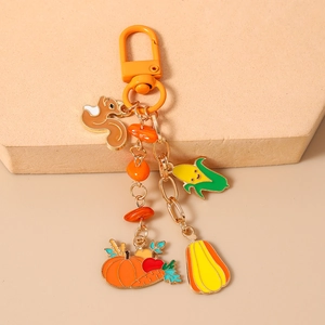 Detailed harvest-themed keychain with squirrel, pumpkin and corn charms on beige stand
