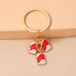 Detail of golden keychain featuring three red and pink dripping oil cola can pendants