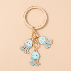 Dettaglio dei ciondoli a forma di medusa cartone con anello d'oro e charms in smalto blu