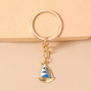 Macro shot of a golden sailing boat keychain with blue and white enamel details