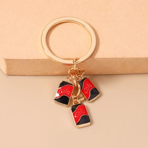 Macro detail of golden keychain with miniature red and black enamel Cola can pendants