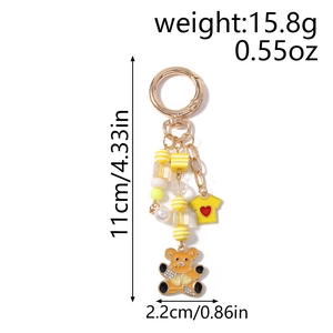 Détail d'un porte-clés ours orange avec pendentif t-shirt jaune et accents de perles nacrées