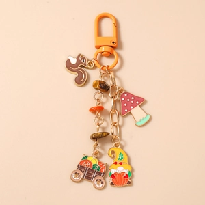 Detail view of squirrel, pumpkin cart, and gnome charms on an autumn-themed keychain